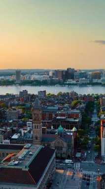 Nehir kıyısındaki çarpıcı düşük katlı şehir mimarisi. Güneşin batışındaki Boston manzarası dikey video.
