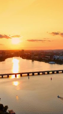 Boston 'un altın saatindeki göz kamaştırıcı manzarası. Şehir manzarası batan güneşin turuncu ışığıyla aydınlanıyor. Turuncu gökyüzü nehire yansıyor. Üst görünüm... dikey görüntü