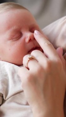 Uyuyan bebeğini elinde tutan bir annenin görüntüsü. Anne parmağıyla çocuğunun burnuna dokunur. Kapat.. dikey video