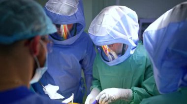 Koruyucu kasklı erkek cerrahlar farklı aletler ve süngerler kullanır. Doktorlar travmayı ameliyat ederler..