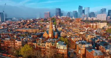 Turuncu cepheli, parlak güneşli eski moda tuğla binalar. İHA görüntüleri şehir merkezindeki sis kaplı yüksek katlı binaya yaklaşıyor. Boston, Massachusetts, ABD.
