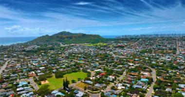 Yeşil vadide birden fazla ev inşa edilir. Diamond Head Krateri ve arka planda yüksek katlı ufuk çizgisi. Honolulu, Hawaii, ABD 'de hava perspektifi.