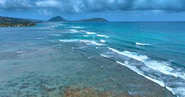 Kıyıya güzel dalgalar geliyor. Gökyüzünde dramatik bulutlar var. Hawaii, ABD.