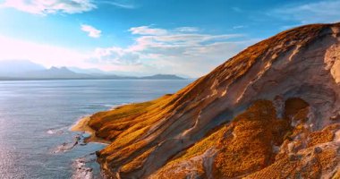 Su manzarasının arka planında kayanın çıplak yamaçları. Arka planda dağ silueti var. Hawaii, ABD.