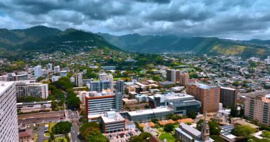 Uçsuz bucaksız şehri çevreleyen yeşil dağlara yaklaşıyoruz. Güzel Honolulu, Hawaii, ABD üzerindeki dramatik bulutlar gökyüzünü kaplıyor. Hava görünümü.