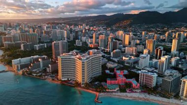 Waikiki, Honolulu, Hawaii, ABD 'deki çok katlı binaların cephelerinde gün batımı. Karanlık dağlar ve arka planda ağır bulutlar. Hava perspektifi.