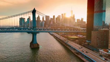 Doğu Nehri 'nin Manhattan Köprüsü' ne yaklaşıyoruz. Arka planda gökdelenlerin arkasında güneş batıyor. New York, ABD.