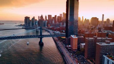 Doğu Nehri 'nin rıhtımı ve gün batımında köprüler. Su manzarasının üstündeki drone görüntüleri Manhattan 'ın gökdelenlerini gösteriyor..