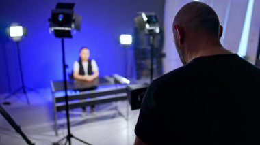 Kameranın önünde duran bir erkeğin arka görüntüsü. Kadın blogcu blogu için video hazırlıyor.