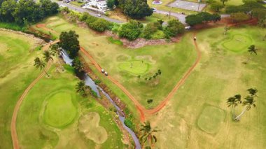 Sahada golf oynayan dört adama yaklaşıyoruz. Hawaii, ABD 'de spor sahasına hava perspektifi.