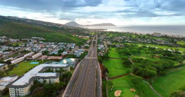 Resimli kentsel alanı geçen çok şeritli otoyol. Yeşil park ve yerleşim alanı boyunca İHA görüntüleri. Oahu, Hawaii, ABD.