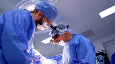 İşbirliği yapan iki cerrah ameliyatta çalışıyor. Nöroşirürjide meşgul olan doktorlara düşük açılı bakış açısı.