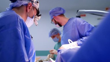 Sağlık ekipleri operasyon yapıyor. Gözlüklü doktor asistanına döner ve enstrümanı bekler. Nöroşirürji devam ediyor..