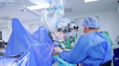 Mikroskop başında oturan bir doktordan uzaklaşmak. Beyin cerrahının beyin üzerinde yaptığı ameliyatın arka görüntüsü..