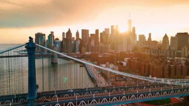 Çarpıcı Manhattan Köprüsü boyunca yükseliyor. Batan güneşin saklandığı Manhattan ufuk çizgisini gösteriyor. Hava görünümü.