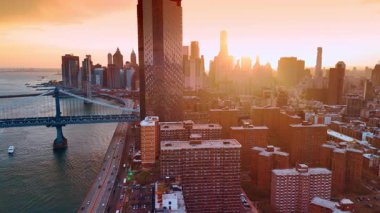 Batan güneşin yumuşak ışığı Manhattan 'ın manzarasını kamaştırır. Günbatımında Doğu Nehri 'nin su manzarasının üstündeki drone görüntüleri..