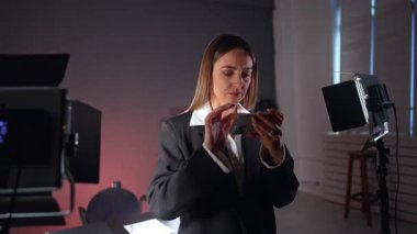 Gri ceketli güzel esmer beyaz kadın telefonuna odaklanmış görünüyor. Kadın blogcu, çorapların yanında dikilip videoyu kontrol ediyor.