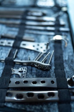 Sergilenen metal aletler koleksiyonu. Koyu bir keçeli yüzey üzerinde düzgün düzenlenmiş çeşitli metal aletlerin detaylı görünümü.