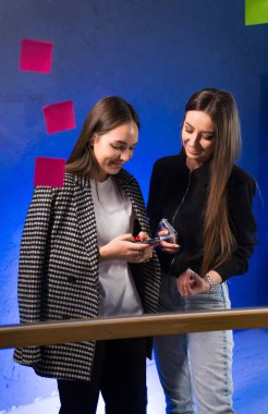 İki kadın birlikte yaratıyor. İki genç kadın, akıllı telefon kullanırken ve canlı bir çalışma alanında fikirleri tartışırken birlikte hareket ediyorlar..