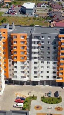 Şehirde çağdaş konut binası. İHA görüntüsü, modern yüksek apartman binalarının yanında uçuyor. Renkli duvarlar, yeni şehir bölgesinde yer alıyor. Dikey video