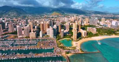 Göz kamaştırıcı plajları ve yat kulübüyle lüks Waikiki tatil köyünden uzakta. Arkaplanda dağların üzerinde ağır bulutlar asılı. Honolulu, Hawaii, ABD. Hava görünümü.