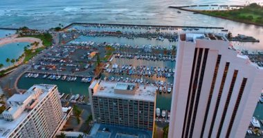 Rıhtımdaki binaların tepelerinden aşağı iniyorlar. Sahildeki büyük yat kulübü. Honolulu, Hawaii, ABD.