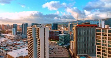 Şehrin üzerinde uçarak büyük otoparka yaklaşıyor. Honolulu, Hawaii, ABD havadan bakıldığında. Kabarık bulutlar arka planda gökyüzünde süzülür.