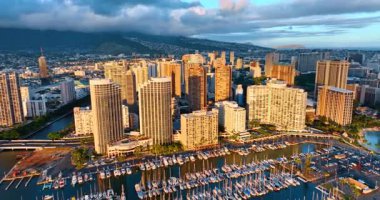 Çok katlı binalar parlak batan güneşle aydınlatılır. Sahilde büyük bir yat kulübü var. Waikiki, Honolulu, Hawaii, ABD. Hava görünümü.