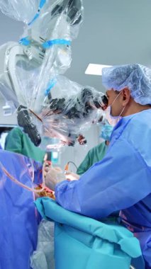 Cerrah hastaya mikroskop kullanarak bakıyor. Ameliyat yapan bir doktordan uzaklaşmak. Dikey video.