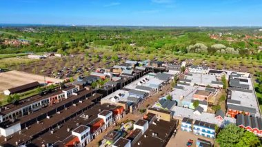 Teraslı evlerin ve sokakların üzerinde uçuyor. Yeşilliğin arka planındaki otoparklara yaklaşıyoruz. Hava görüntüsü. Lelystad, Hollanda.
