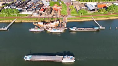 Batavia gemisinin yeniden yapılandırılmasından ve etrafındaki diğer teknelerden uzakta. Mavna su kenarında hareket ediyor. Lelystad, Hollanda 'nın şehir manzarası.