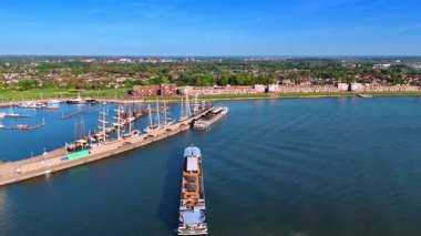 Limana giden bir mavna. Güneşli bir günde Hollanda, Lelystad marinasına hava perspektifi. Arkaplanda yeşil şehir manzarası.