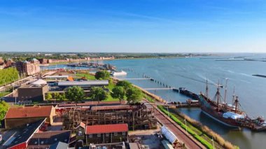 Açık güneşli bir günde Hollanda, Lelystad Panoraması. Batavialand Müzesi 'ne Batavia gemisinin yeniden inşasıyla yaklaşıyoruz. Hava görünümü.