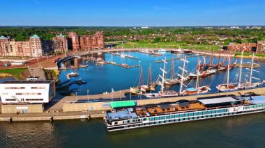 Limandaki rıhtımlarda çeşitli su taşımacılığı. Lelystad, Hollanda 'nın güneşli marinası. Arkasında güzel binalar olan yeşil şehir manzarası. Hava görünümü.