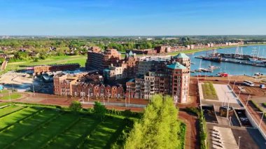 Hollanda 'nın Lelystad kıyısındaki inanılmaz mimari kompleksi. Arka planda yelkenli tekneleri olan güzel bir marina. Hava görünümü.