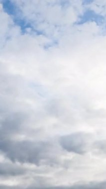 Gökyüzünü yoğun bulutlar kaplıyor. Beyaz bulutlar griye dönüşüyor. Düşük açı. Zaman ayarlı. Dikey video