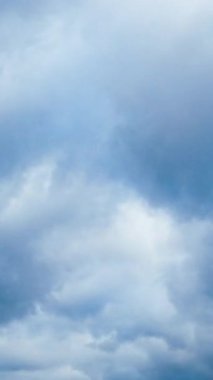 Kabarık gri bulutlar atmosferde yüzüyor. Düşük perspektiften kasvetli gökyüzü. Dikey video