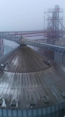 Büyük endüstriyel asansör konteynırları hava manzaralı. Metal tahıl asansör inşaatı. Dikey video