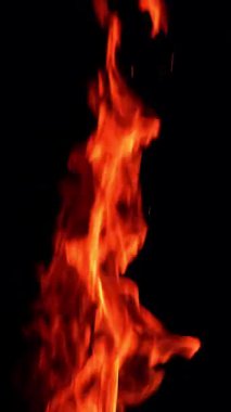 Karanlıkta alevler yükseliyor. Şenlik ateşinden izole edilmiş diller. Dikey video