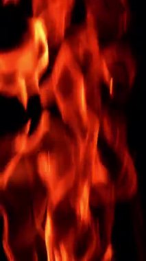 Alevler yanıyor ve yükseliyor. Kapatın. Siyah zemin. Dikey video