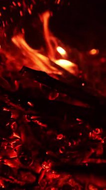 Tanınmayan kampçı kamp ateşinde közleri sopayla hareket ettiriyor. Şenlik ateşi sönüyor. Dikey video