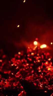 Bilinmeyen kişi yangını söndürüyor. Yanan közler çok güzel parlıyor. Siyah zemin. Dikey video