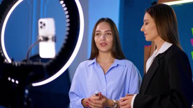 Çekici Kafkasyalı esmerler halka ışığı ve akıllı telefon başında dururlar. Blogcular video içeriğini alan kameraya konuşur ve hareket ederler.