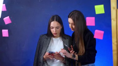 İki tane uzun saçlı kadın şu telefona bakıyorlar. Konsantre bayanlar bilgi arıyor ya da video izliyor.