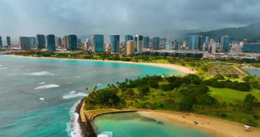 Pasifik Okyanusu kıyısında çarpıcı yeşil parkı ve kumlu plajı var. Waikiki 'nin modern ufuk çizgisi bulutlu gökyüzünün altında. Hava görünümü.