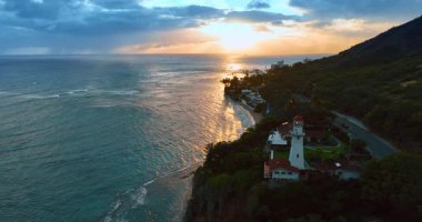 Resimli yeşil sahildeki deniz feneri. Pasifik Okyanusu kıyısında güzel bir günbatımı. Hawaii, ABD.