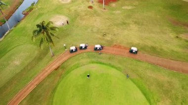 Büyük sahada golf oynayan çok az adam var. Rüzgarlı bir günde spor sahasının üstünde drone görüntüleri. Hawaii, ABD.