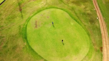 Golf yavruları olan iki adam çimleri biçilmiş bir şekilde tarlanın yanından geçiyor. Hawaii, ABD 'deki golf sahasının en iyi manzarası..