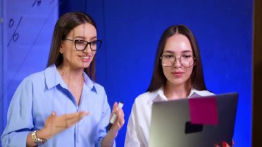 Dizüstü bilgisayarda işbirliği yapan iki kadın. İki kadın birlikte çalışıyor, modern bir çalışma alanında fikirleri tartışırken bir laptopta verileri gözden geçiriyorlar..