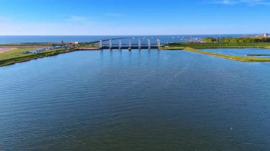 Hollanda 'da günbatımı manzarası. Hollanda 'nın sakin suları gün batımının canlı renklerini yansıtıyor. Köprüler ve yelkenliler manzarayı güzelleştiriyor..
